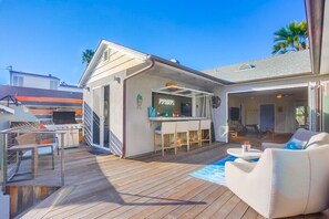A spacious outdoor deck with a barbecue, a bar area, and comfortable seating.