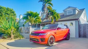 A red SUV parked in a driveway with a house in the background. - Amazing Beach House! 2 Yards w/ Hot Tub + Fire Pit (San Diego)