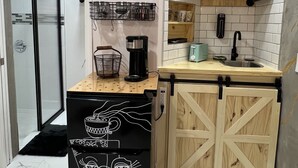 A compact kitchen with a coffee station, a microwave, and a sink.