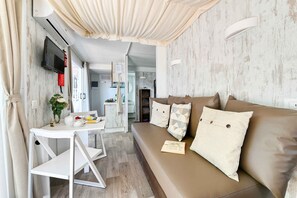 A modern living room with a sofa, a small table, and a TV mounted on the wall. - Mobilehome with air conditioning, terrace and pool (Peschiera del Garda)