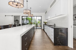Una cocina moderna con una isla grande, armarios oscuros e iluminación colgante.