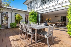 Enjoy dining and socializing in this beautifully landscaped outdoor space with a wooden deck and comfortable seating.