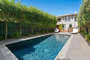 Relax by the pool surrounded by a paved deck and lounge chairs.