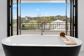 Relax in a spacious bathroom with a bathtub and large windows offering views of the surrounding area.