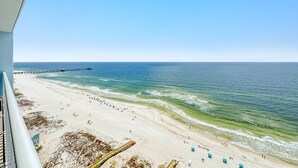 Una spiaggia con un molo che si protende sull'oceano, sabbia fine e cielo sereno.