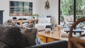 A cozy living room with a wooden coffee table, a sofa, and a large painting on the wall.