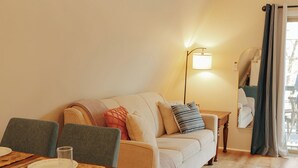 A cozy living room with a sofa, a dining table set with plates and glasses, a floor lamp, and a large mirror reflecting the room. - Secluded A frame cabin close Dells, BRAND NEW HOT TUB, firepit, grill. (Oxford)