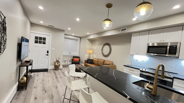 Uma cozinha moderna com uma ilha central, banquetas, micro-ondas e pia.