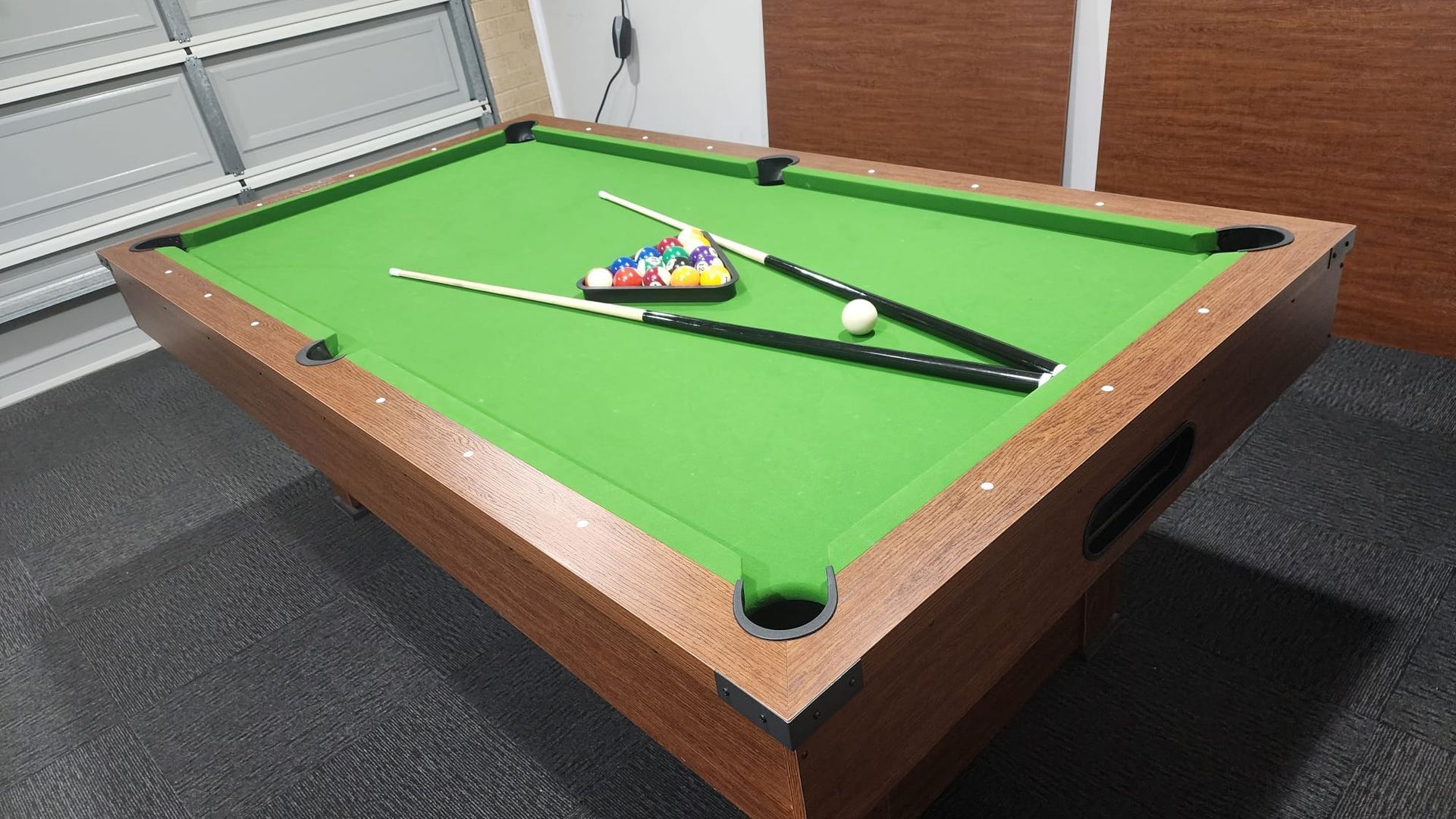 Une table de billard recouverte d’un drap vert, entourée d’un cadre en bois.