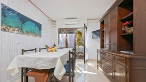 Una zona de menjador amb una taula preparada per a dues persones, un armari de fusta amb calaixos i un quadre a la paret.