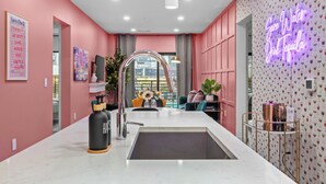 Una cocina moderna con una isla central, un letrero de neón y vistas a través de una ventana.