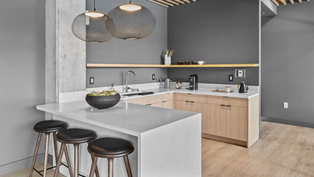 Una cocina moderna con una isla grande, taburetes de bar, iluminación colgante y armarios de madera.