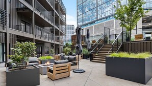 Un área de estar exterior moderna con macetas, sofás y una chimenea.