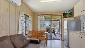 Una habitación acogedora con sofá, paredes de madera, televisor y refrigerador.