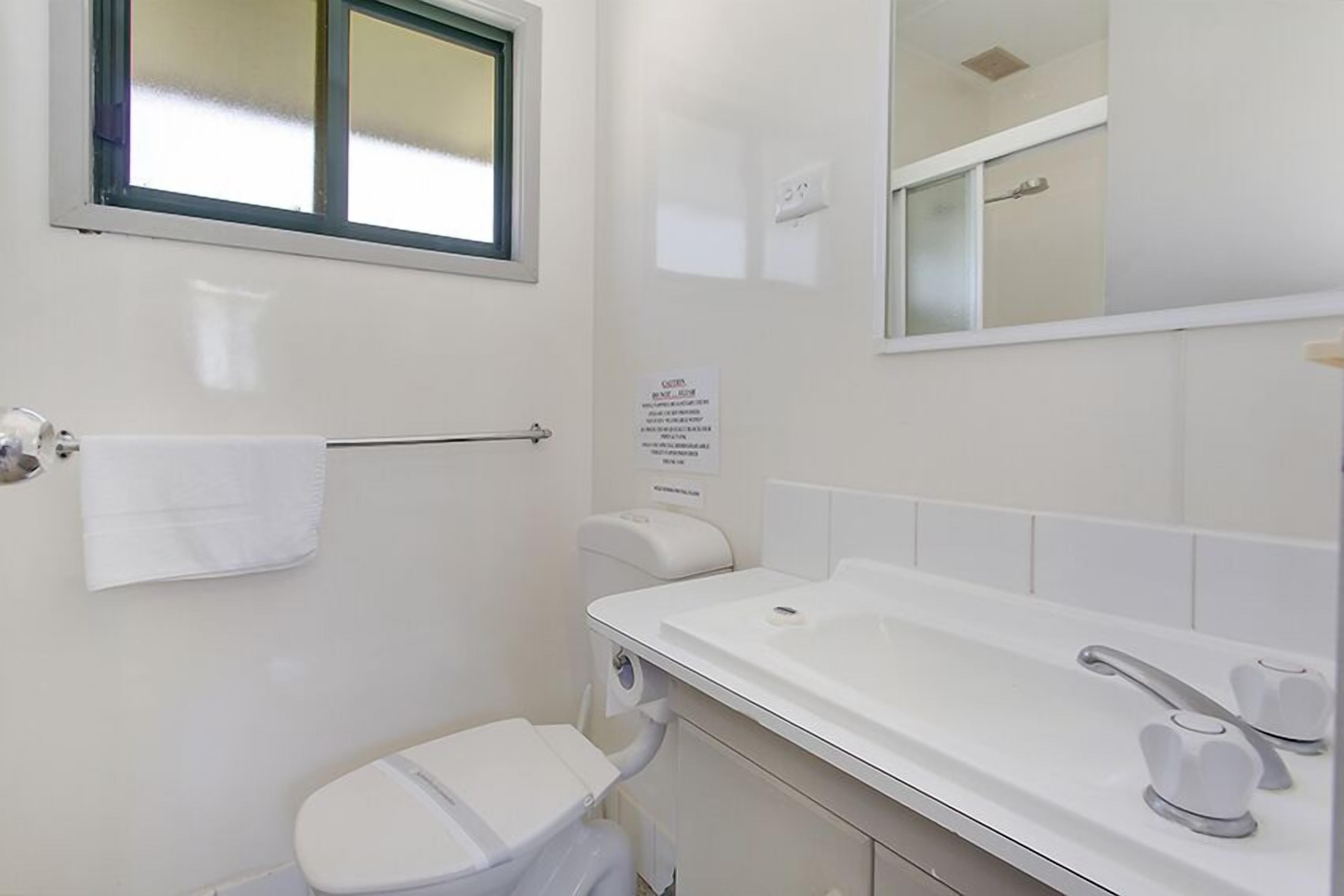 A small, clean bathroom with a toilet, sink, and mirror.
