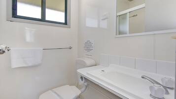 A small, clean bathroom with a toilet, sink, and mirror.