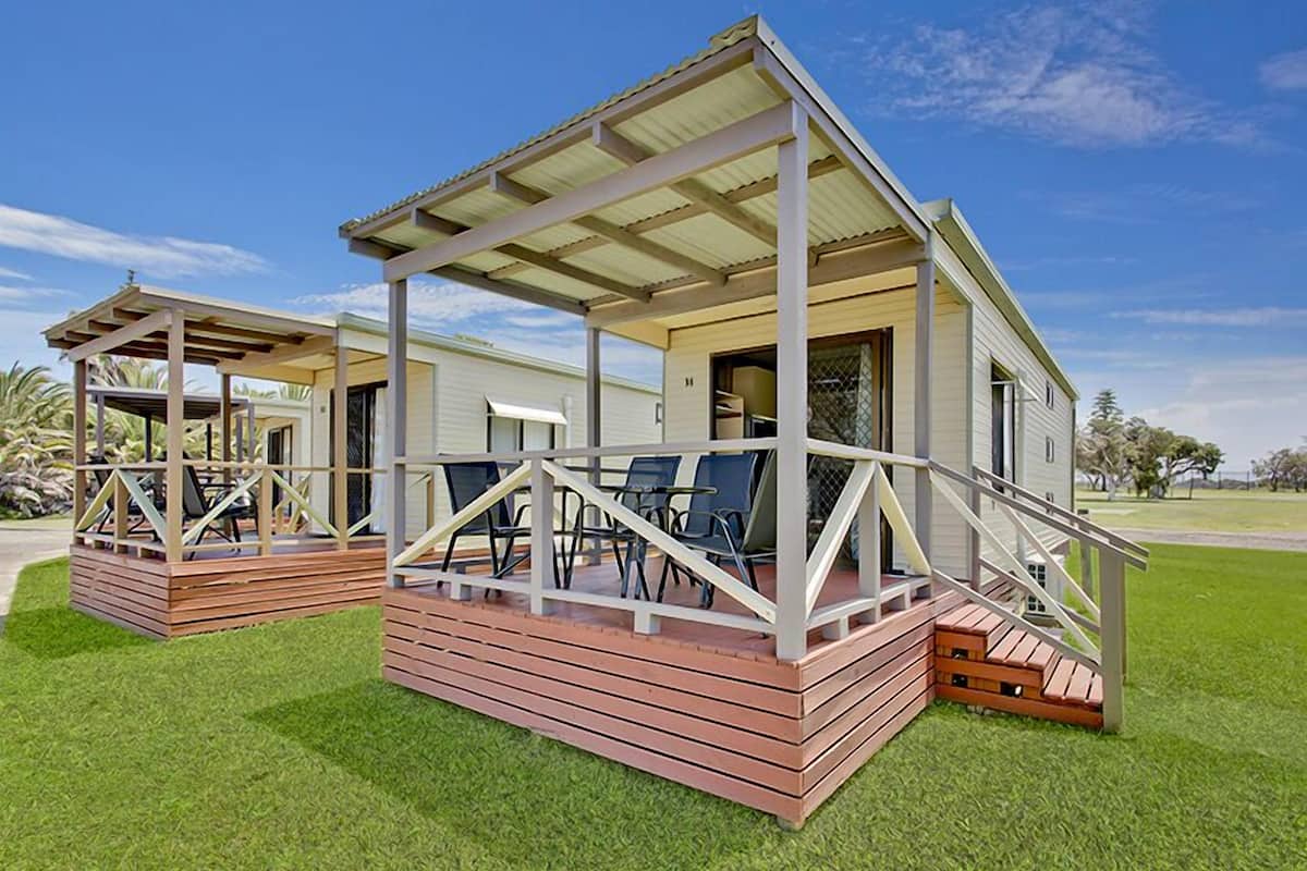 Una casa de dos pisos con un porche cubierto, una escalera y una pequeña terraza.