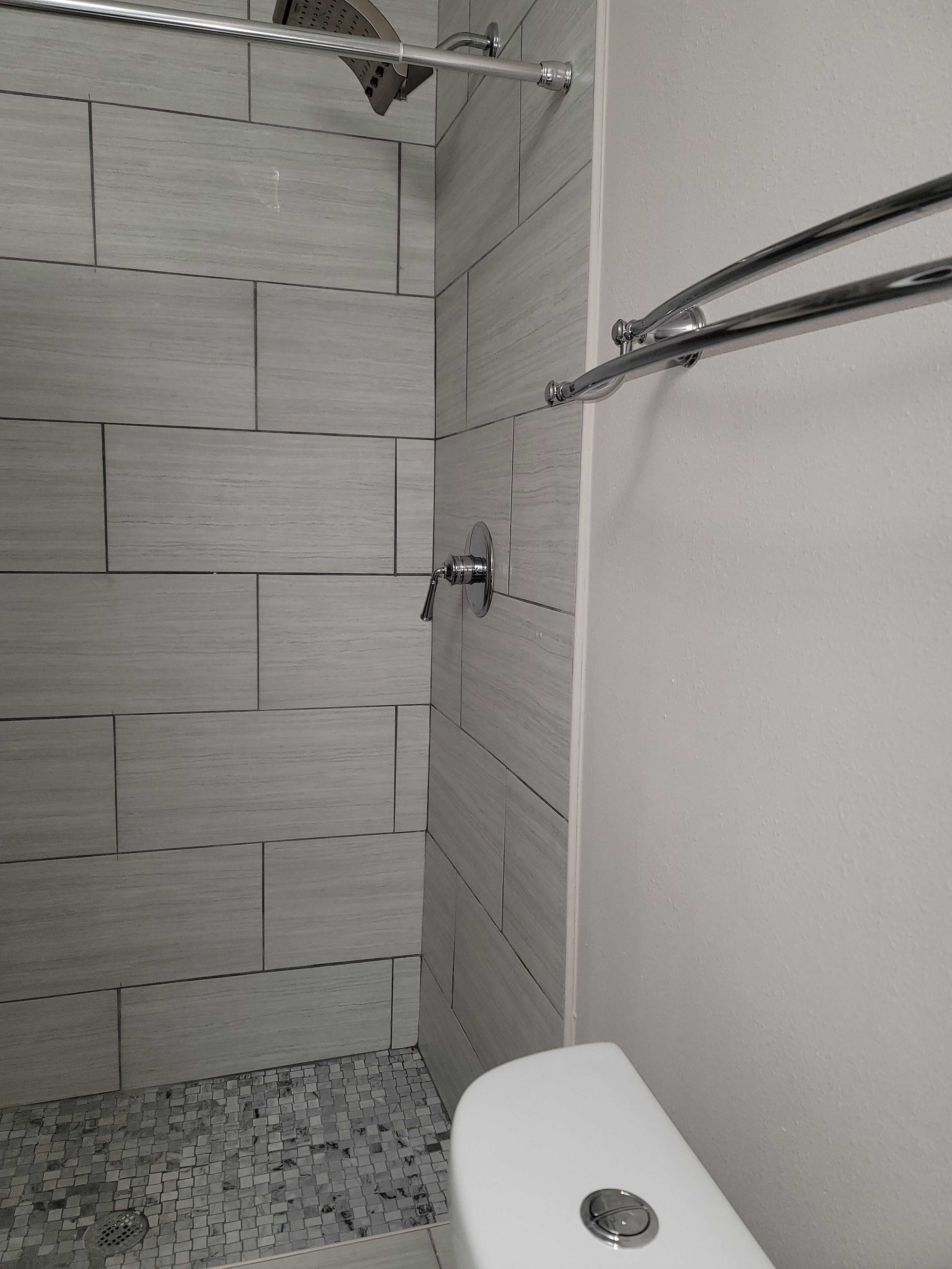 A bathroom with a shower area, tiled walls, and a toilet.