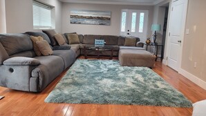 Ein Wohnzimmer mit einem Ecksofa, einem Couchtisch und einem flauschigen Teppich.