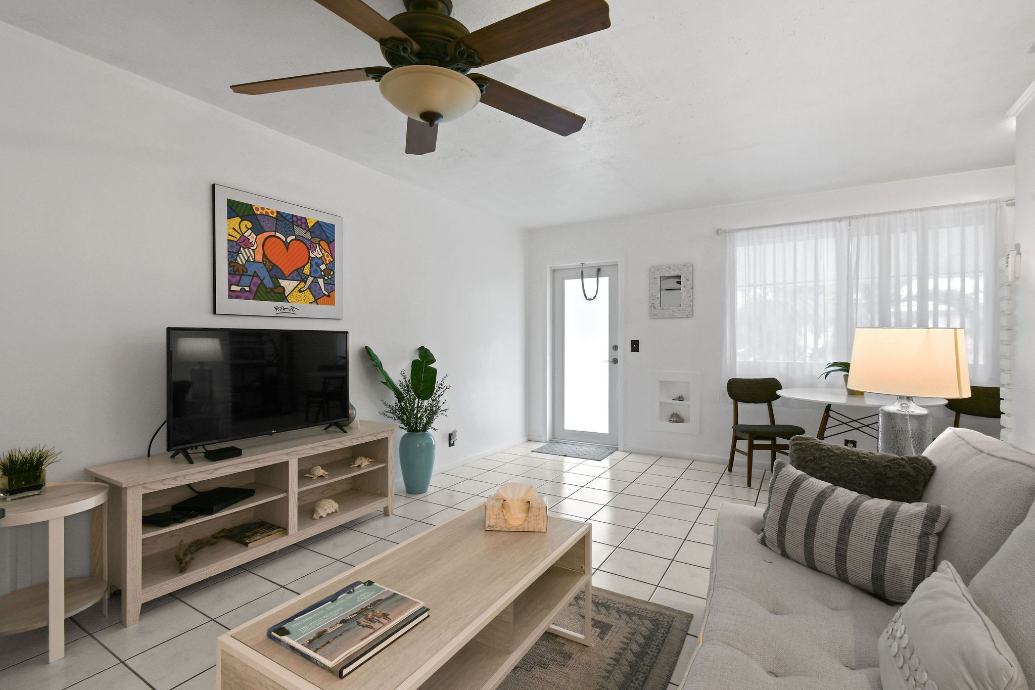 A modern living room with a flat-screen TV, wooden entertainment unit, and a ceiling fan.