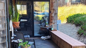 Une terrasse extérieure couverte avec une plateforme en bois, un espace salon et une variété de plantes en pot.