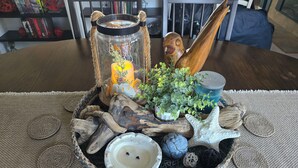 Un élément décoratif central composé d’une bougie, d’une étoile de mer et de divers éléments naturels, le tout disposé sur un set de table en fibres tressées.