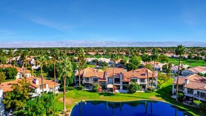 A residential area with houses, a swimming pool, and a mountain range in the background. - This 1525 SqFt Upper condo Has been updated. Beautiful lake and mountain views (La Quinta)