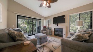 A living room with a fireplace, a ceiling fan, and a large window with blinds. - This 1525 SqFt Upper condo Has been updated. Beautiful lake and mountain views (La Quinta)