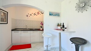 A modern kitchen with white cabinets, a red rug, a white bar stool, and a decorative wall clock. - Gorgeous apartment in Sveti Lovrec (Sveti Lovrec)