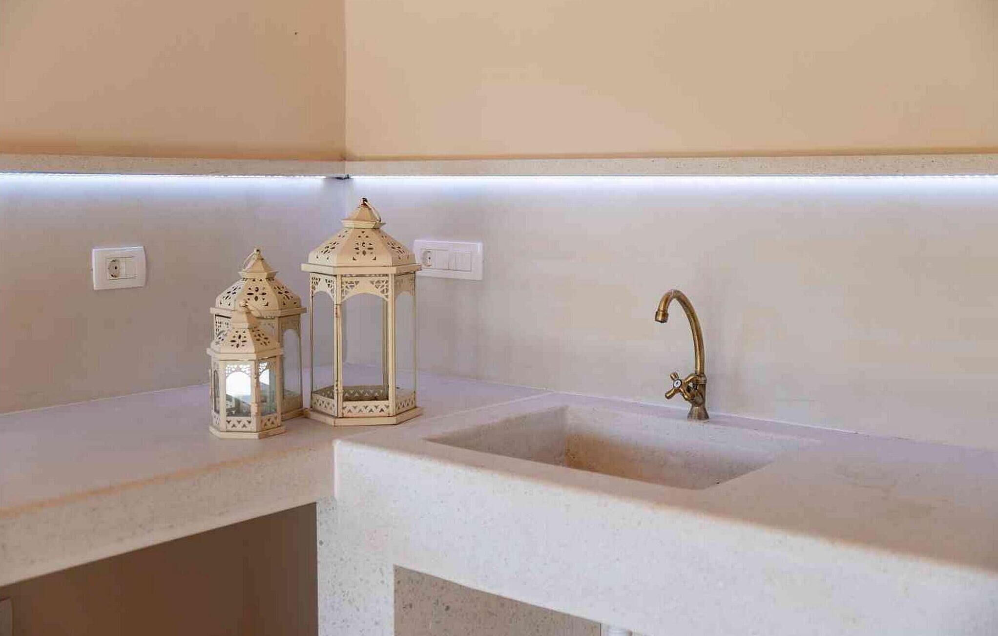A bathroom with a white sink, a gold faucet, and two ornate white lanterns on the countertop.