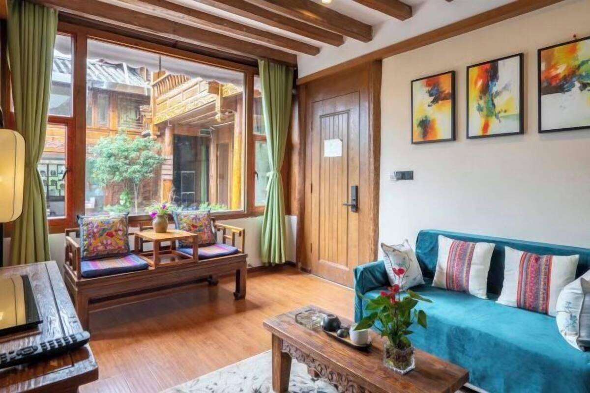 Ein gemütliches Zimmer mit einer hölzernen Bank, einem Sofa, einem Tisch mit einer Vase und einem Fenster mit Vorhängen.