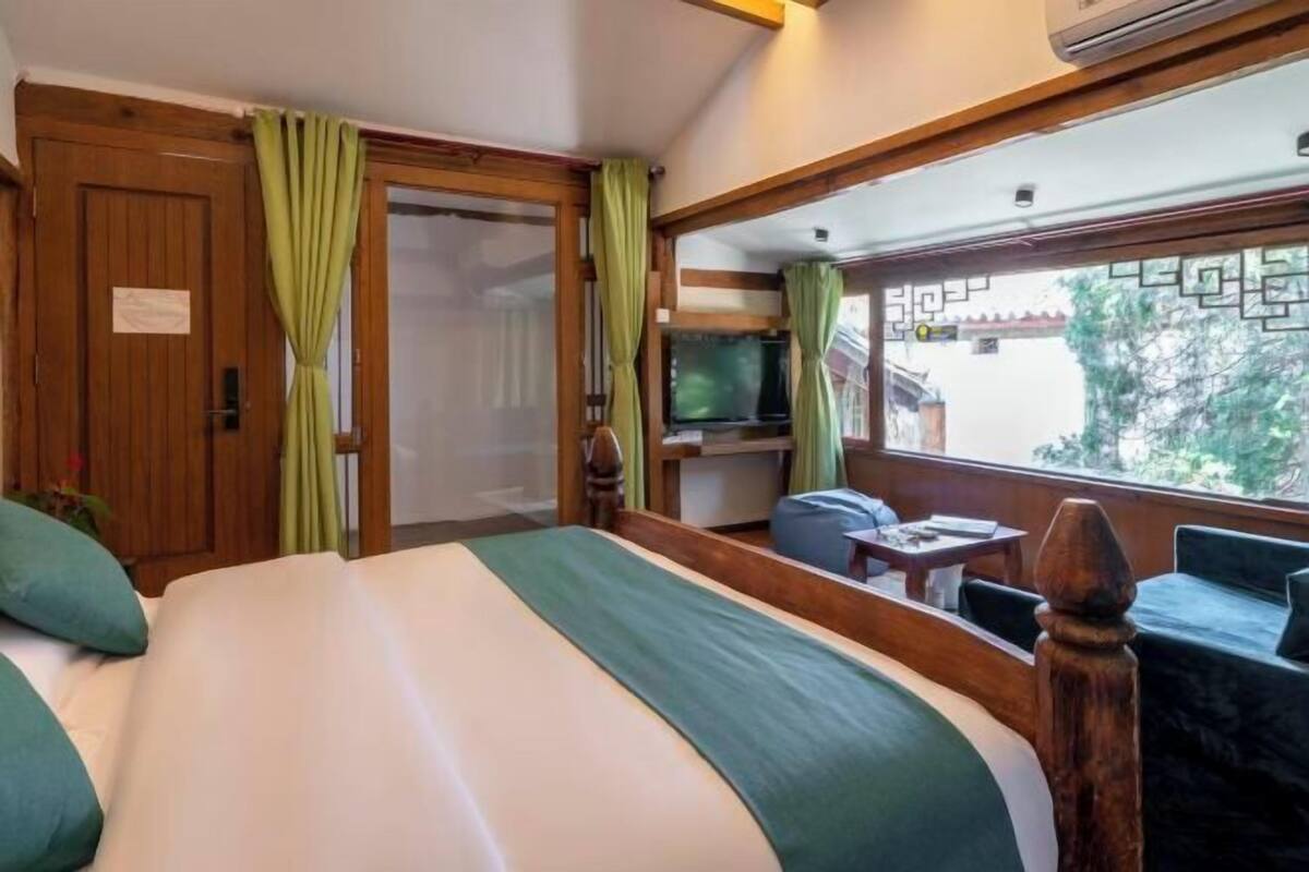 Ein Hotelzimmer mit Bett, Fernseher, kleinem Tisch und Blick nach draußen.