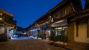 A traditional street with buildings, a paved road, and some greenery.