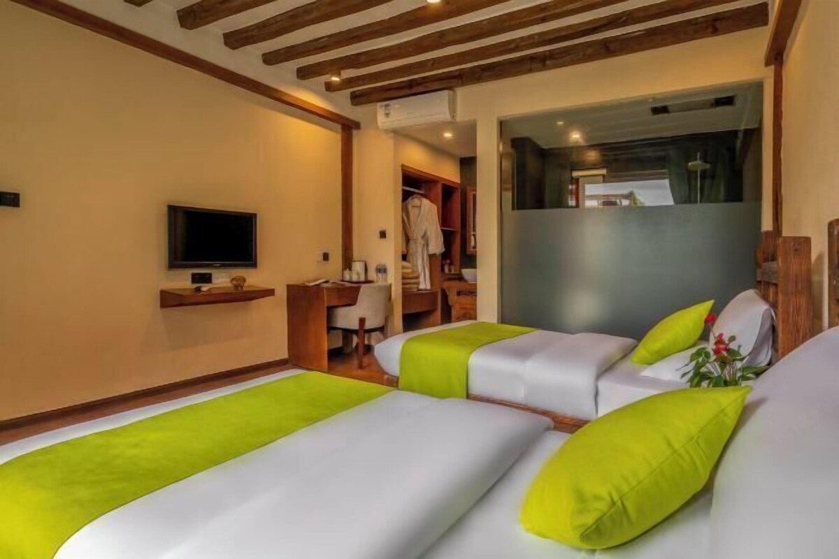 Habitació d'hotel amb dos llits, televisió, escriptori i armari.