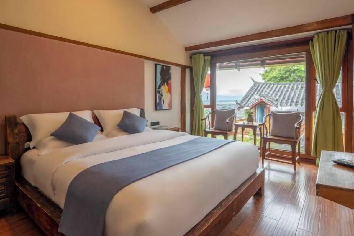Ein Schlafzimmer mit einem großen Bett, einem Holzkopfstück, einem kleinen Tisch und einem Stuhl.
