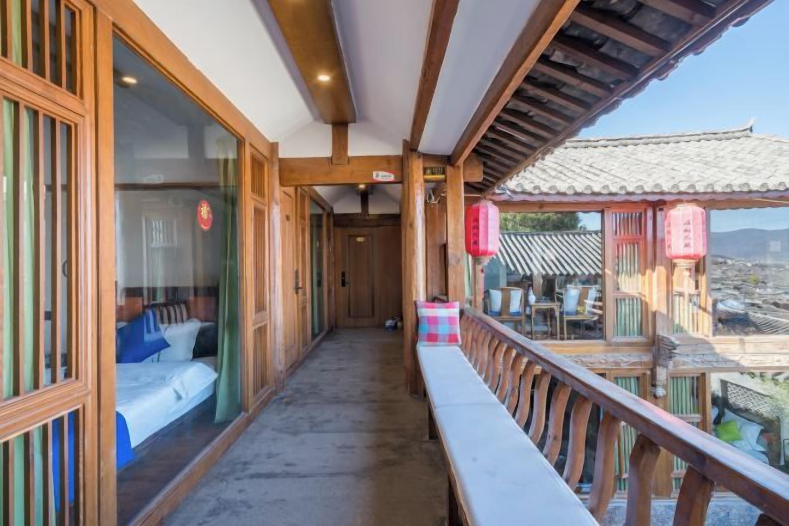 Un balcon avec une balustrade en bois, un lit avec un matelas blanc et une literie bleue, et un bâtiment traditionnel de style japonais en arrière-plan.