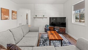 Un salón moderno con un sofá gris, una mesa de centro de madera y un televisor de pantalla plana.