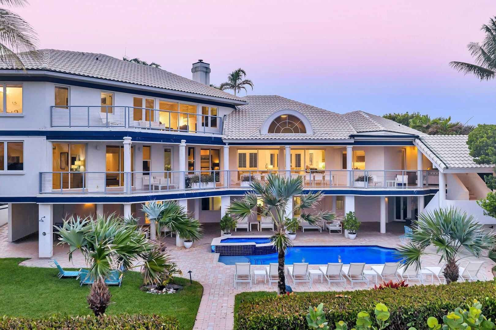 A large two-story house with a swimming pool, outdoor seating, and a covered patio area.