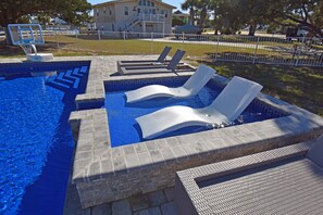 Une piscine avec des chaises longues et un panier de basketball.