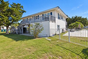 Une maison de plain-pied avec un balcon, un petit jardin devant et une allée d’accès fermée par un portail.