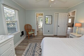 Un dormitorio con cama, cómoda, silla y vista al exterior.