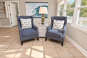 Two patterned armchairs with matching cushions, a white side table with a lamp, and a large wave painting on the wall. - Game Time - Channel Front in Garden City Beach (Garden City Beach)