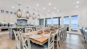A spacious kitchen with white cabinetry, a wooden dining table, and pendant lights. - Jonesin' By The Beach - Ocean Front & Channel Front in Garden City Beach (Garden City Beach)