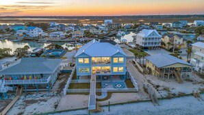 A beachfront property with a two-story house featuring a large balcony, a swimming pool, and a dock. - Jonesin' By The Beach - Ocean Front & Channel Front in Garden City Beach (Garden City Beach)
