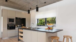 A modern kitchen with a central island, stainless steel appliances, and a large window providing natural light. - Amazing home in Visnjan (Visnjan)