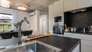 A modern kitchen with stainless steel appliances, a black countertop, and a dining area with a table and chairs. - Amazing home in Visnjan (Visnjan)