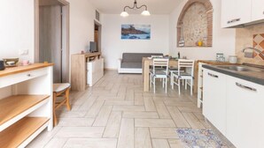 A modern kitchen with a dining area, wooden furniture, and a stone backsplash. - La Casetta dei Pescatori by Interhome (Follonica)