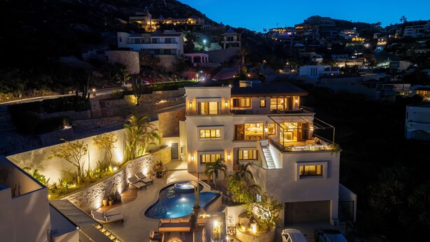 Una casa de varios pisos con piscina, mobiliario exterior y garaje.