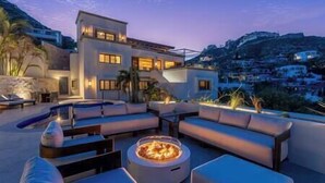 Un espacio al aire libre moderno con una fogata, asientos y una piscina.