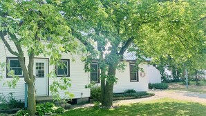 En vit husvagn med två fönster och en liten veranda.